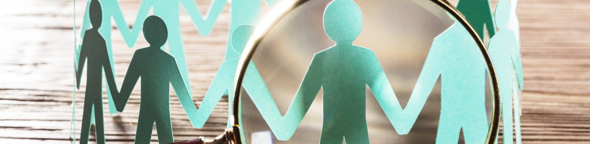 Paper Cut Out Human Figure Seen Through Magnifying Glass Wooden Desk